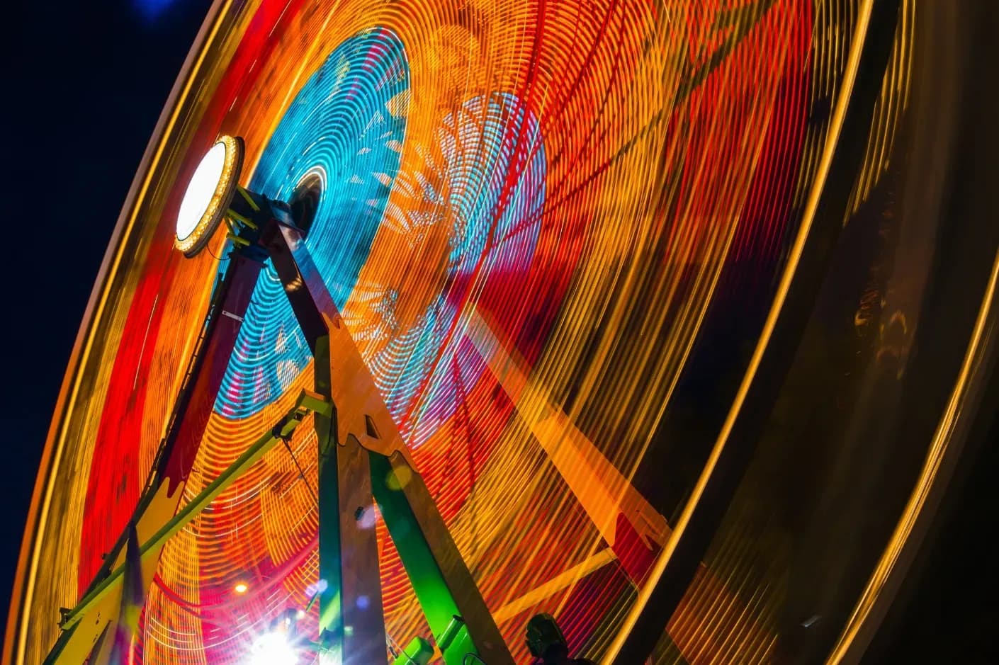A vibrant ferris wheel illuminated against the night sky, showcasing a beautiful array of colors and lights.