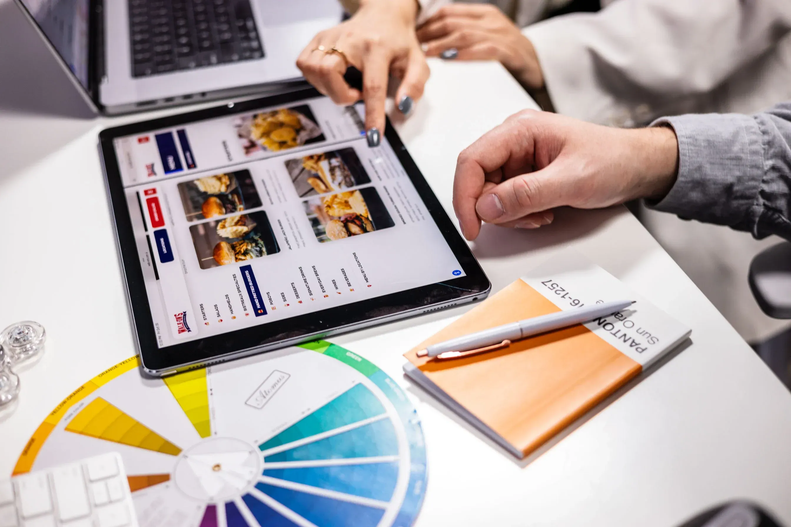 A person using a tablet computer with a menu on it, showcasing web design options.