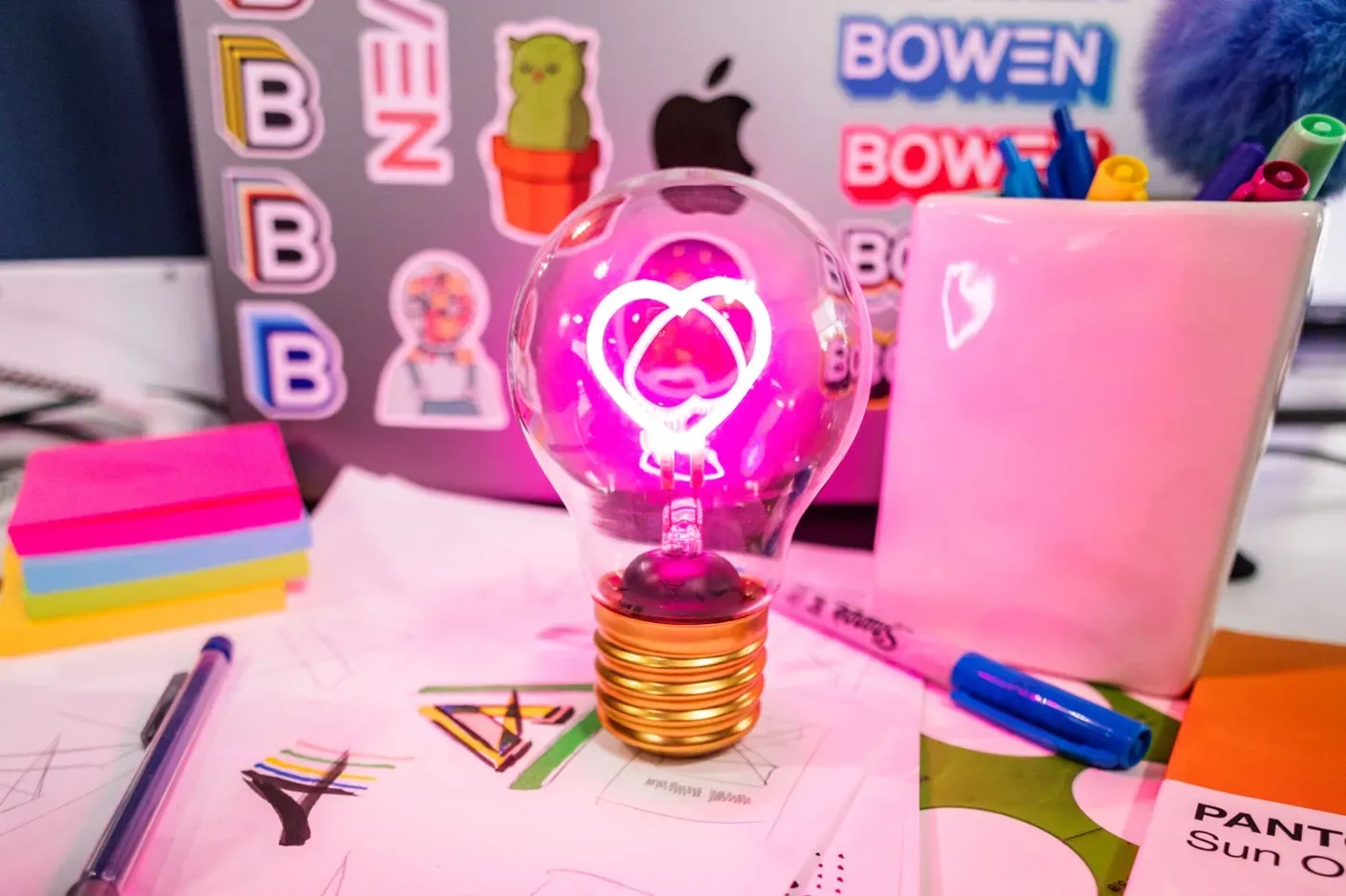 Pink light bulb on desk with laptop and items