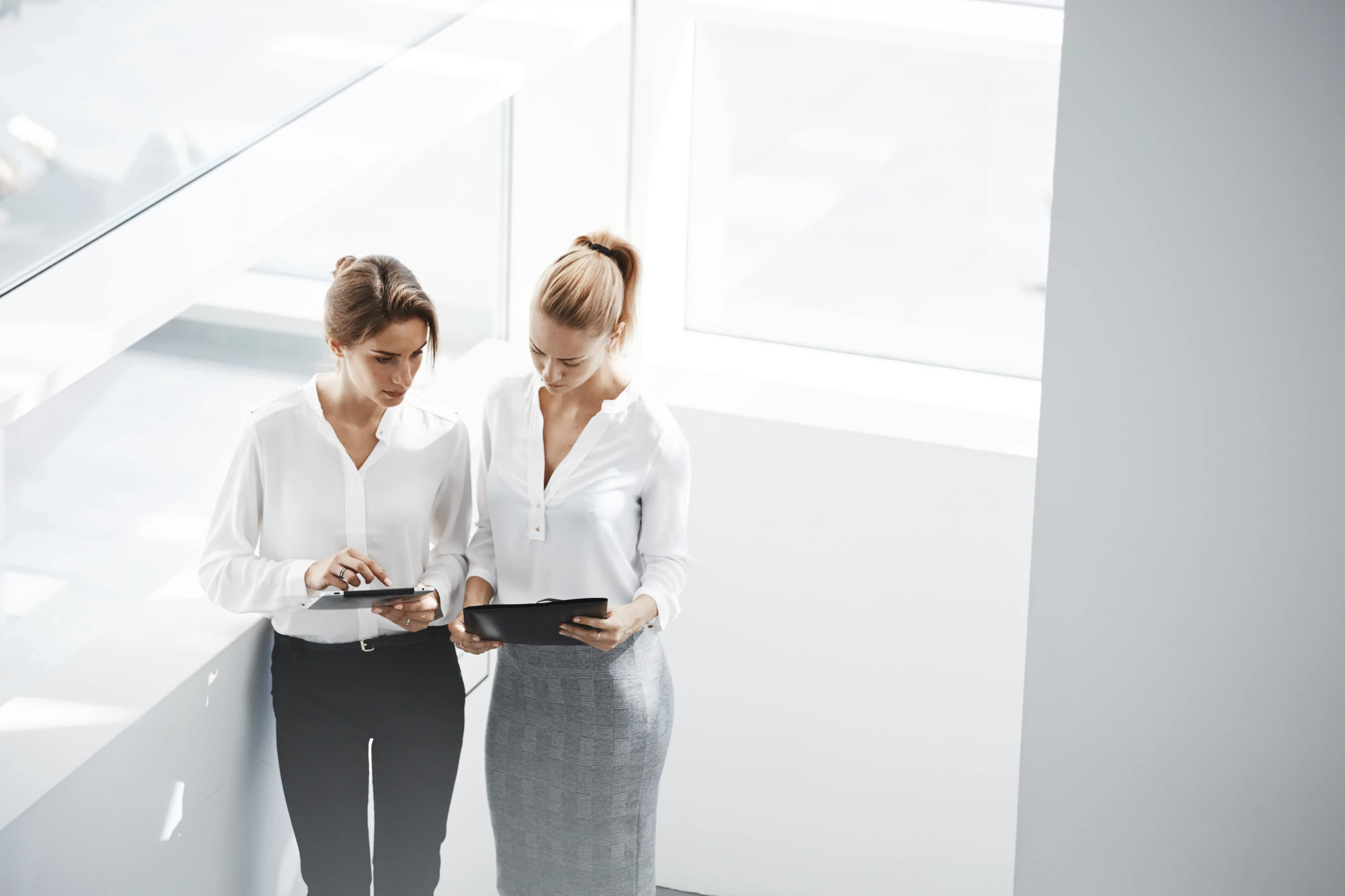 Female entrepreneurs in a meeting, looking at a laptop and discussing business strategies.